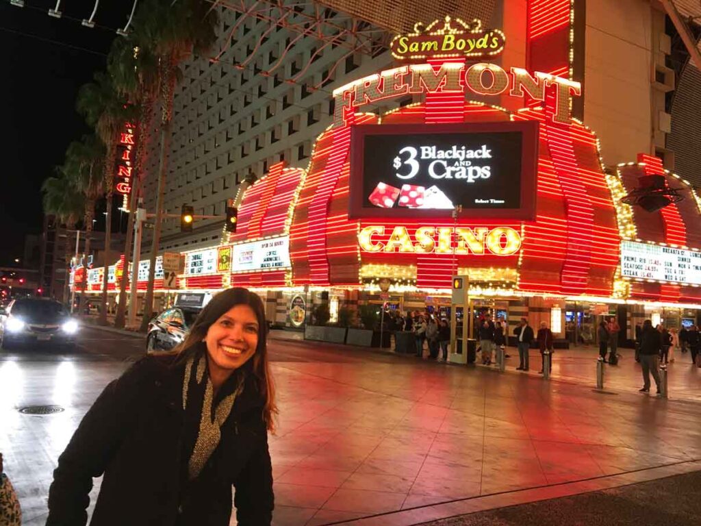 mulher na frente de um cassino iluminado procurando o que fazer em Las Vegas