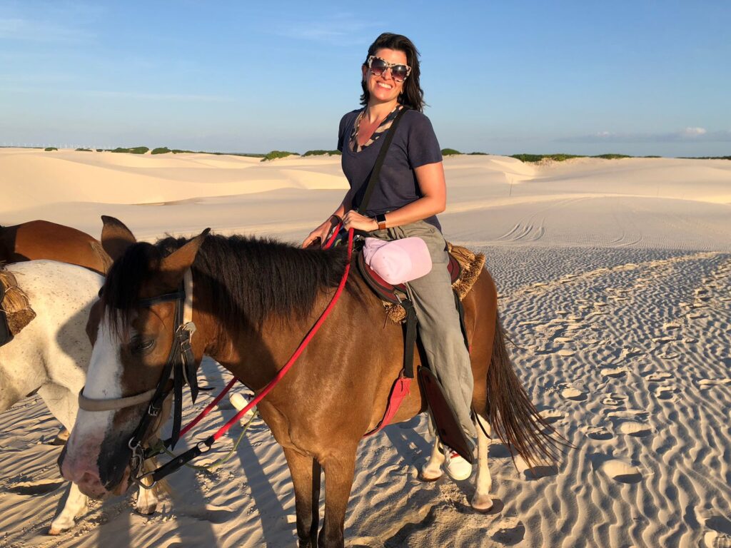 mulher passeando em cavalo marrom pelas dunes dos lençóis maranhenses