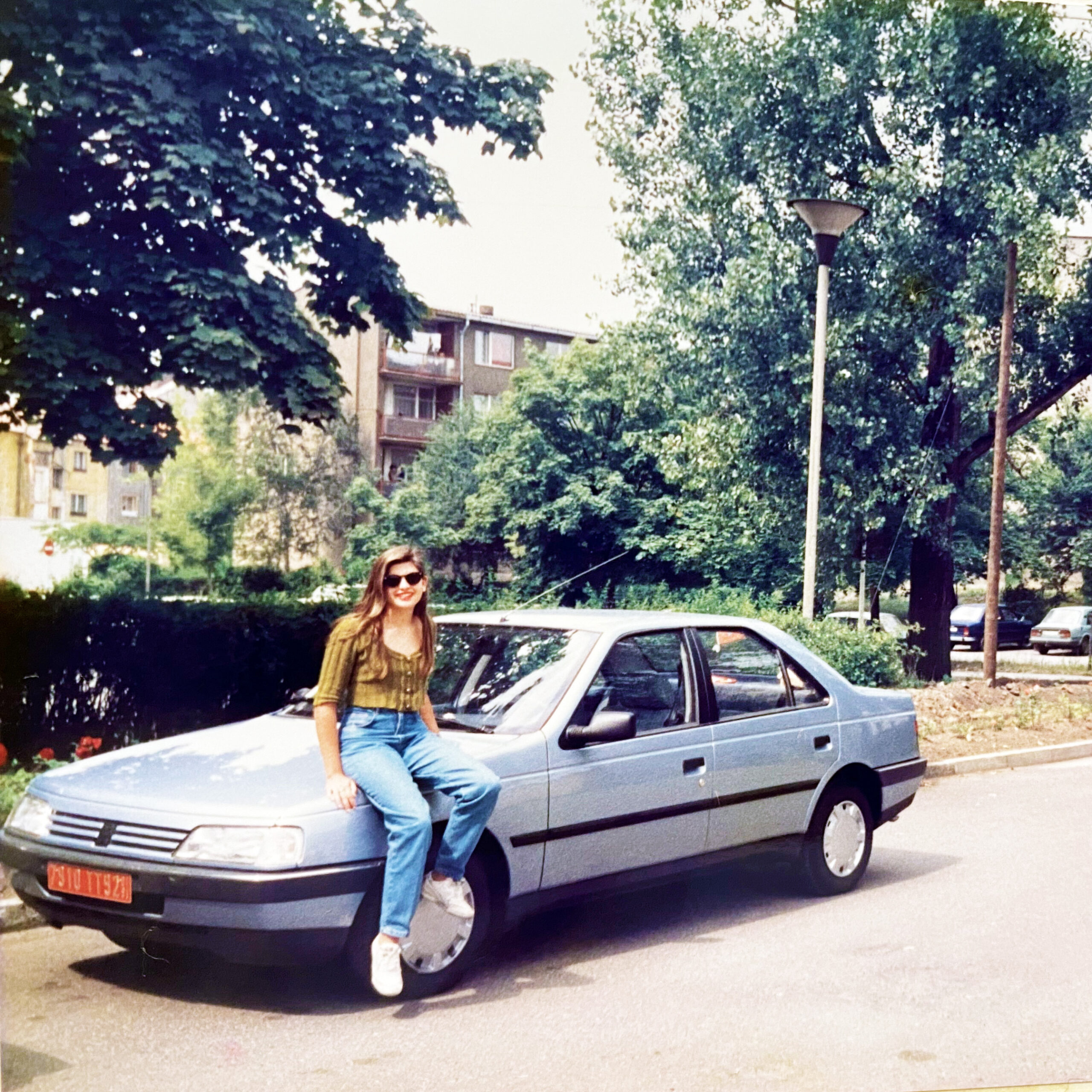 jovem sentada em um carro prata em uma viagem nos anos 90