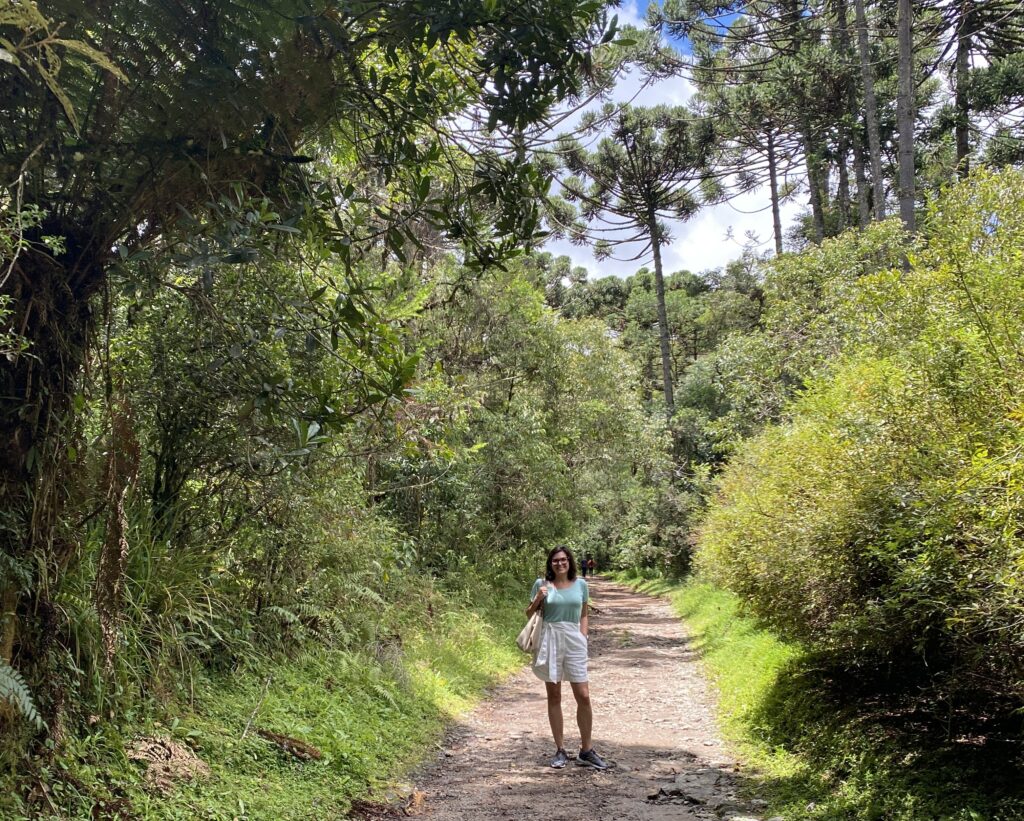 mulher em um passeio pela trilha do Horto Florestal em campos do jordão, cercada de vegetação