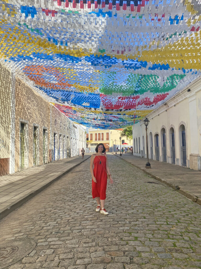 mulher de vestido vermelho posando para foto na Praia Grande em São Luis do Maranhão com bandeirinhas de são joão penduradas na rua