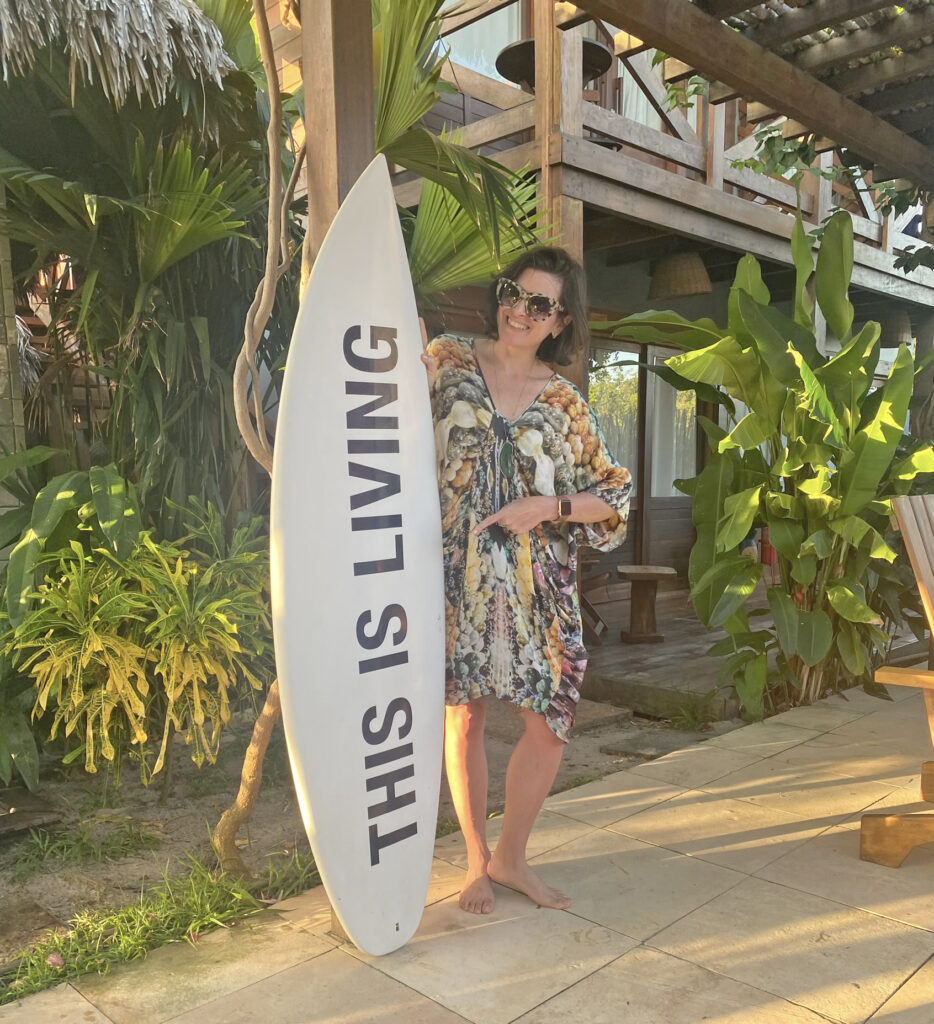 área externa da pousada vila aty, mulher posando para foto com uma prancha de surf