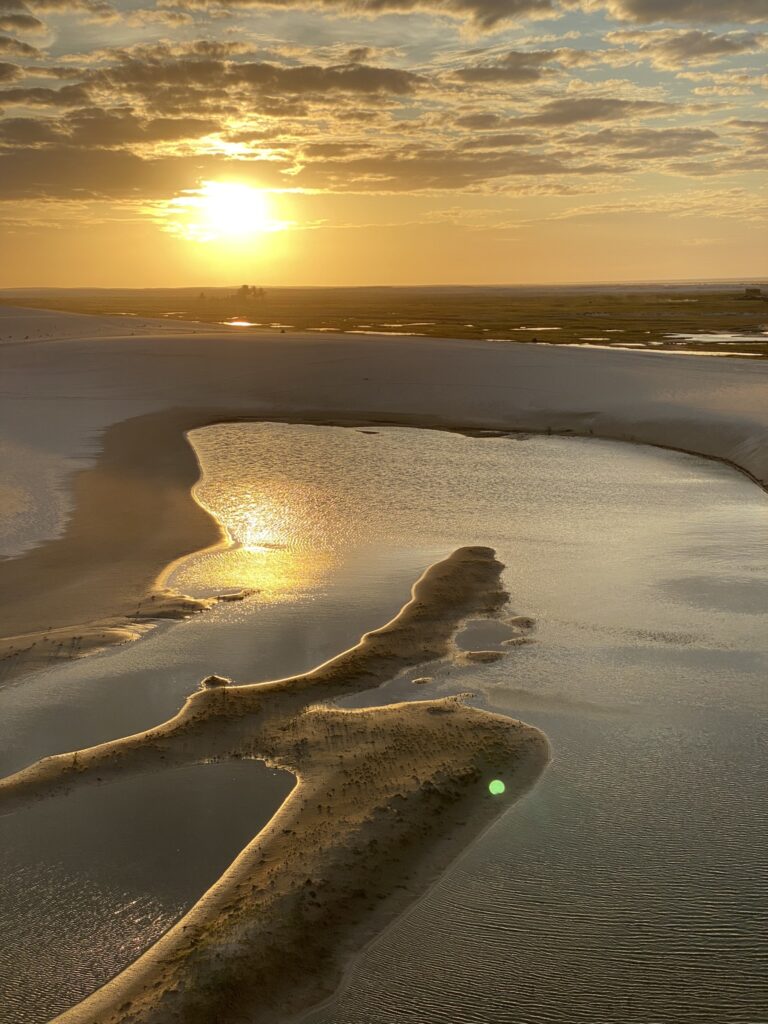 lagoa formada entre dunas e por do sol ao fundo no Maranhão