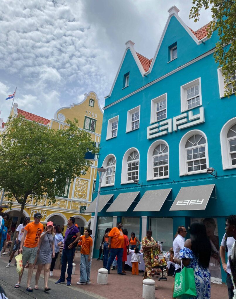 casa azul e pessoas vestidas de laranja para celebrar o dia do rei