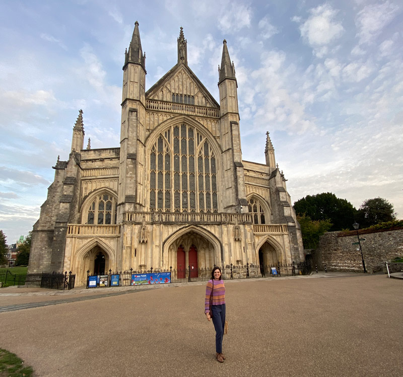 mulher posando na frente da catedral de winchester no final de um dia de sol