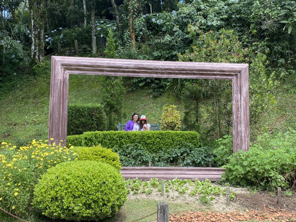 jardins do amantikir em campos do jordao com mae e filha tirando foto dentro de uma moldura de madeira