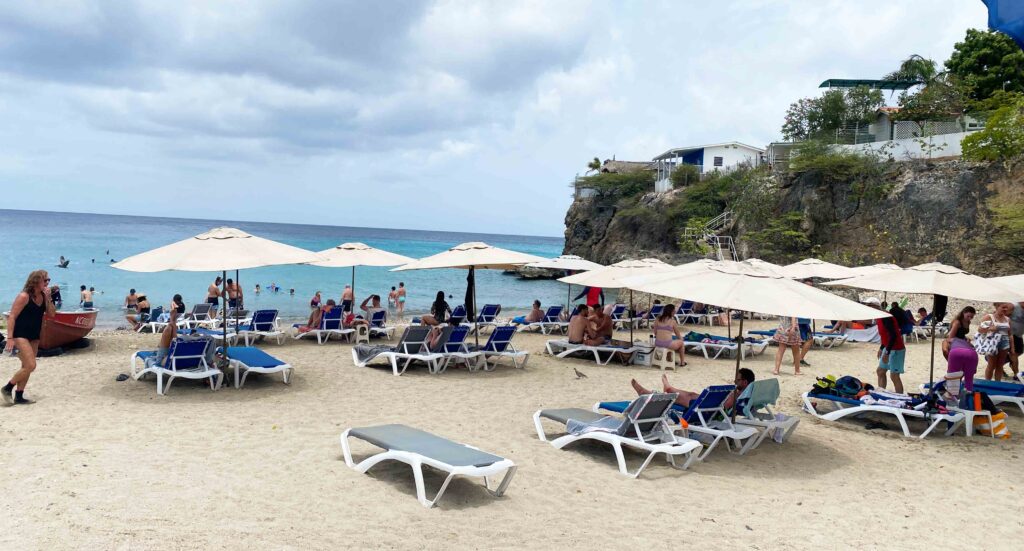 praia com espreguiçadeiras, ombrelones e mar azul em curaçao