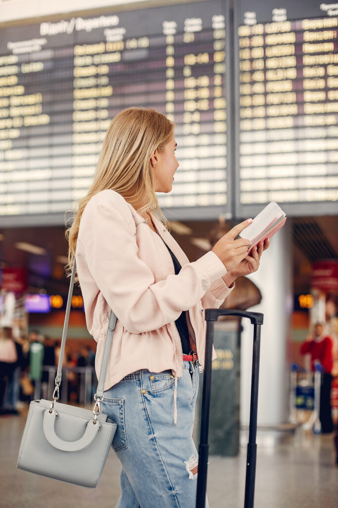 Mulher preocupada com o horário do voo olhando o painel do aeroporto