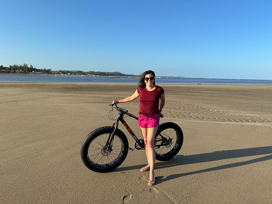mulher fazendo passeio de bicicleta na praia em frente ao resort
