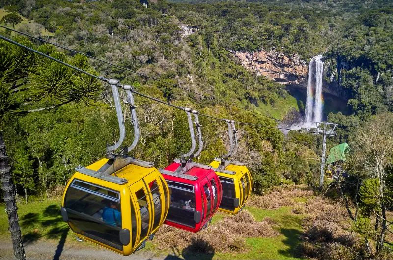 Telefericos coloridos que sobem com vista da cascata do caracol - roteiro do que fazer em Gramado e região