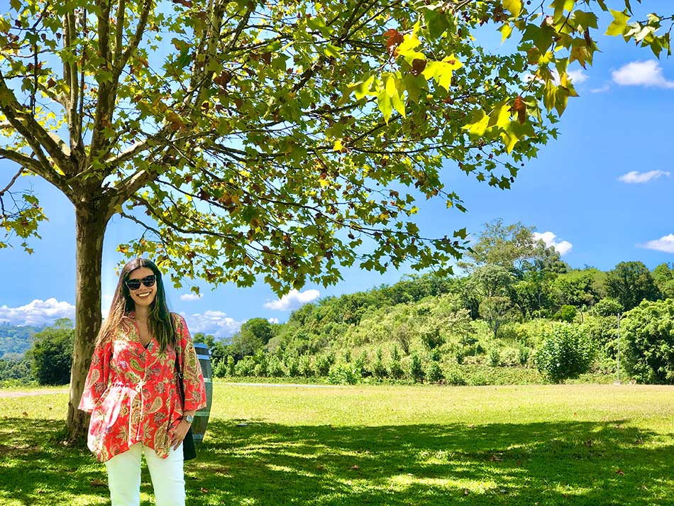 mulher está sendo fotografada em um grande gramado com árvores