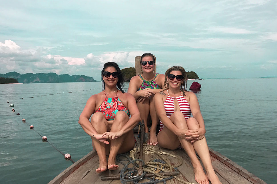 tres mulheres de férias em um barco tradicional na Tailandia