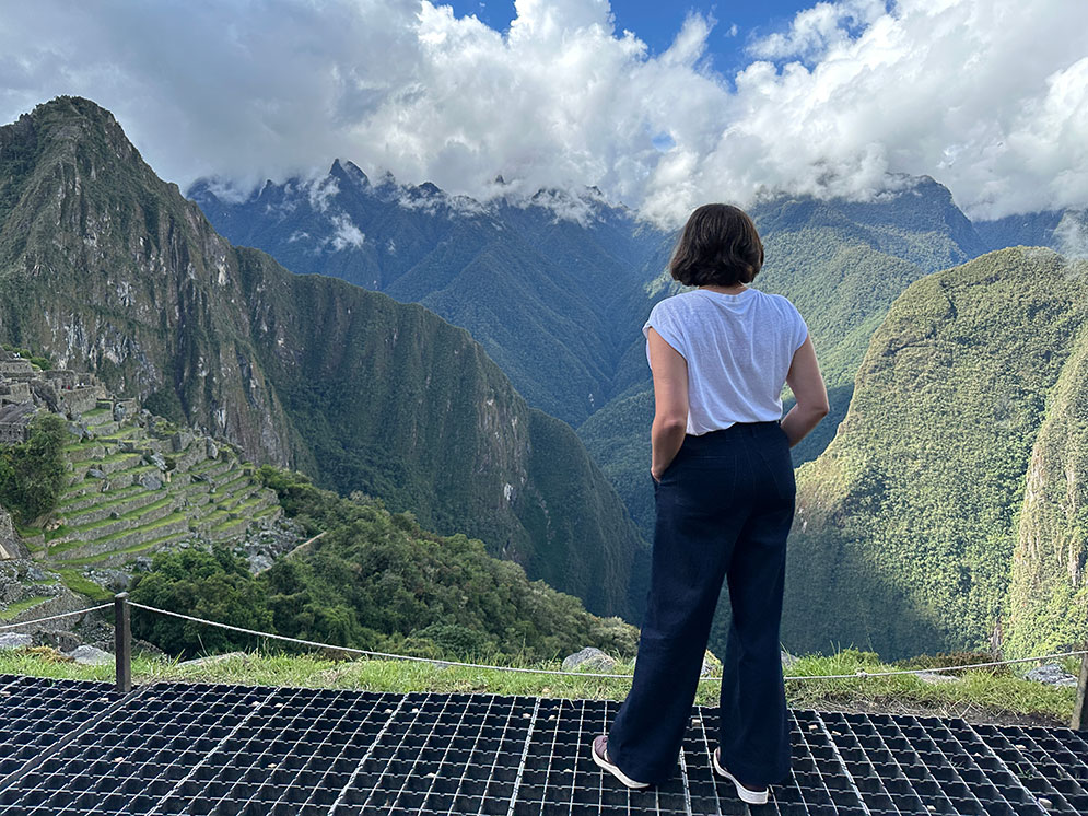 mulher observando as ruinas de machu picchu com a montanha ao fundo