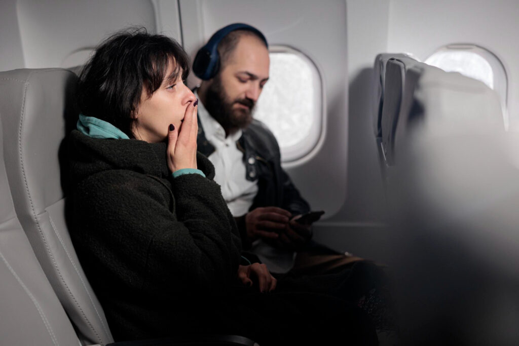 Mulher com cara de cansada viajando de avião